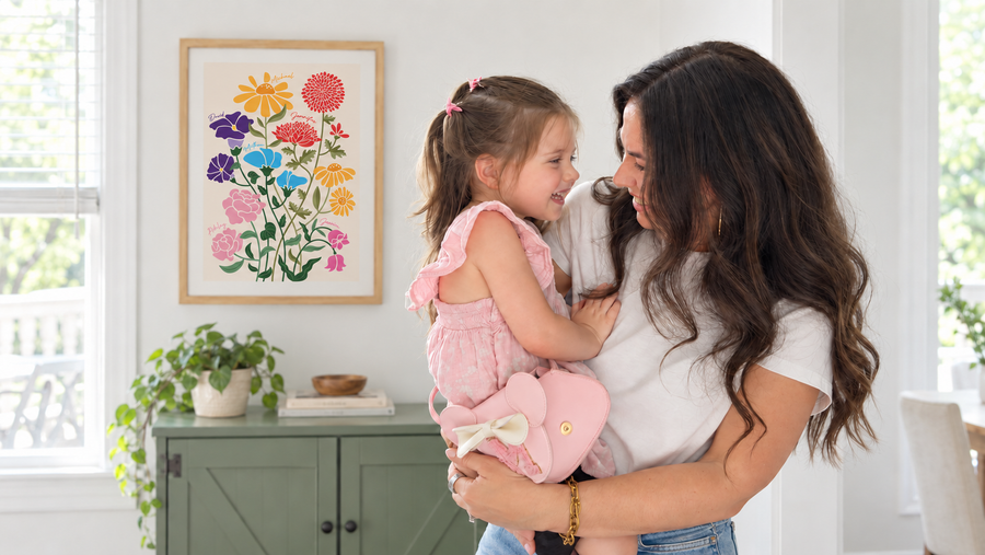 Mother holding her daughter beside a framed personalized Family Garden artwork.